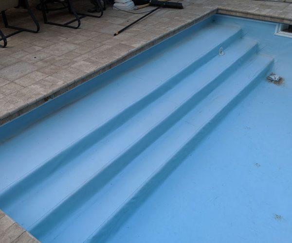 A light blue pool liner shown installed over pool stairs.
